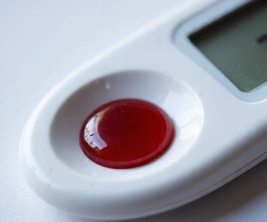 Kropla krwi na glukometrze, symbolizująca kontrolę glukozy